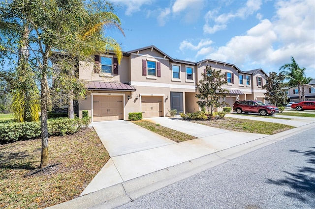 townhome / multi-family property featuring an attached garage, stucco siding, metal roof, driveway, and a standing seam roof