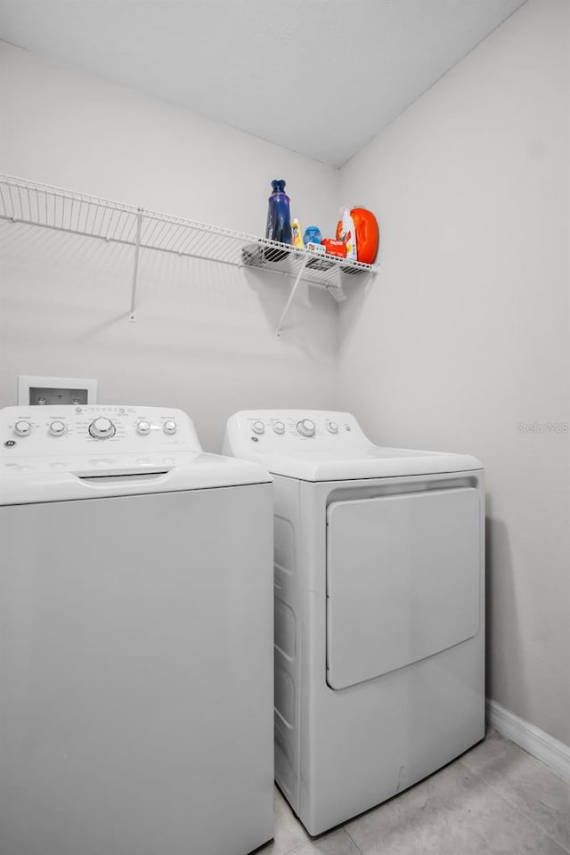 washroom with laundry area, separate washer and dryer, and baseboards