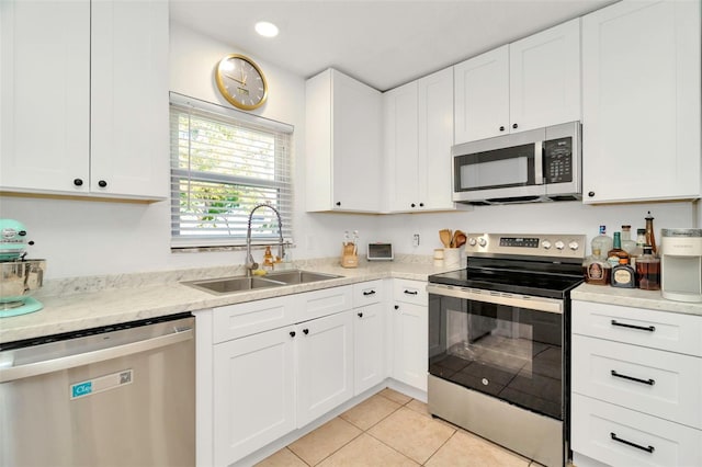 kitchen with a sink, appliances with stainless steel finishes, light tile patterned flooring, and white cabinets