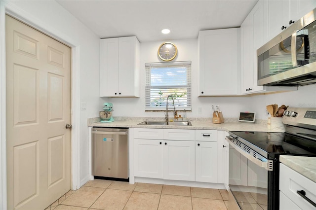 kitchen featuring a sink, light stone counters, white cabinetry, appliances with stainless steel finishes, and light tile patterned flooring