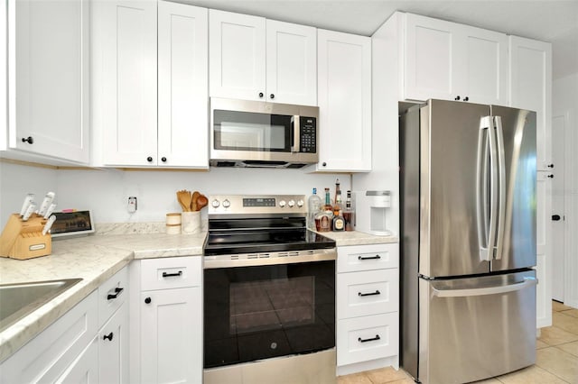 kitchen with light tile patterned floors, appliances with stainless steel finishes, white cabinetry, and light countertops