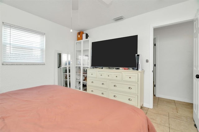 bedroom featuring light tile patterned floors, visible vents, a ceiling fan, and baseboards