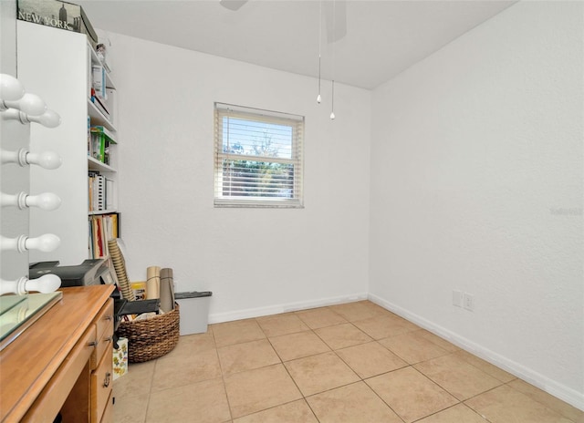 empty room with light tile patterned flooring, baseboards, and a ceiling fan