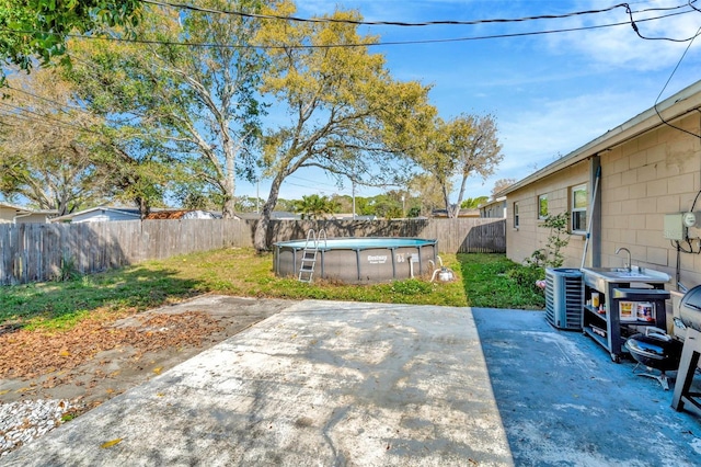 view of yard with a fenced in pool, central air condition unit, a fenced backyard, and a patio area