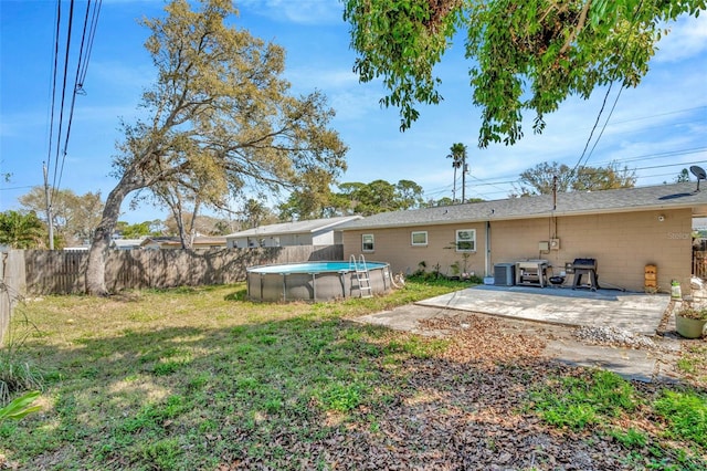 rear view of house with a patio, fence, a yard, a fenced in pool, and concrete block siding