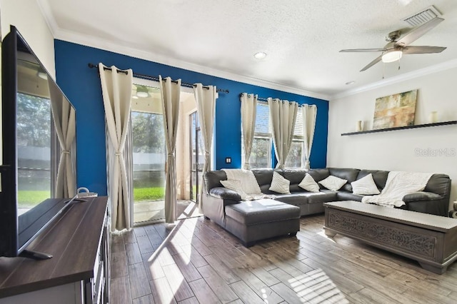 living area featuring visible vents, a ceiling fan, a textured ceiling, wood finished floors, and crown molding