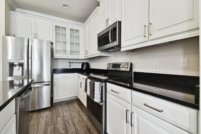 kitchen featuring dark countertops, appliances with stainless steel finishes, white cabinets, and dark wood-style flooring