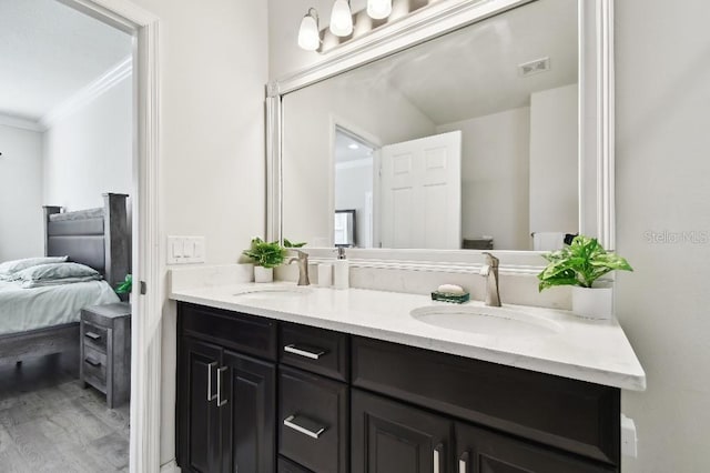 ensuite bathroom featuring a sink, visible vents, double vanity, and crown molding