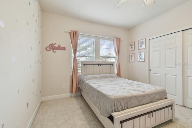 bedroom with light carpet, a closet, baseboards, and a ceiling fan