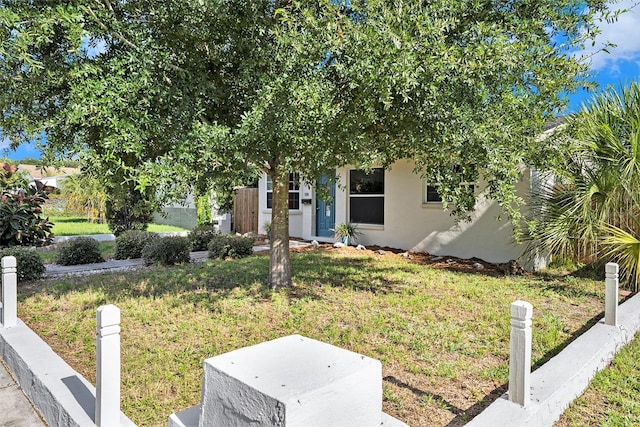 obstructed view of property with stucco siding and a front lawn