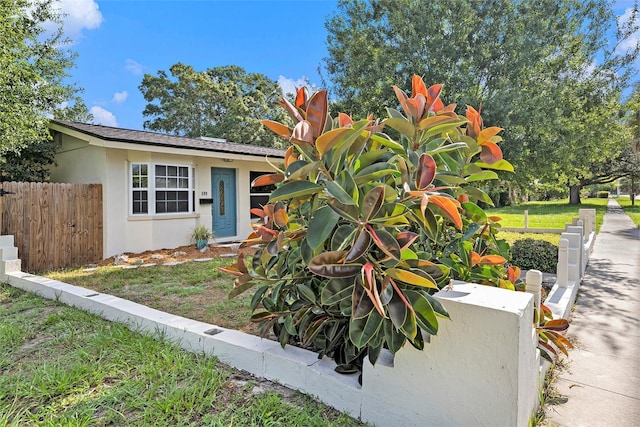 view of front of property featuring a front yard, fence, and stucco siding