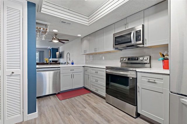 kitchen featuring visible vents, light countertops, light wood-style floors, appliances with stainless steel finishes, and backsplash