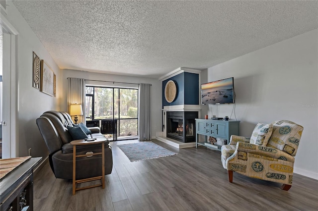 living area featuring wood finished floors, a multi sided fireplace, and a textured ceiling