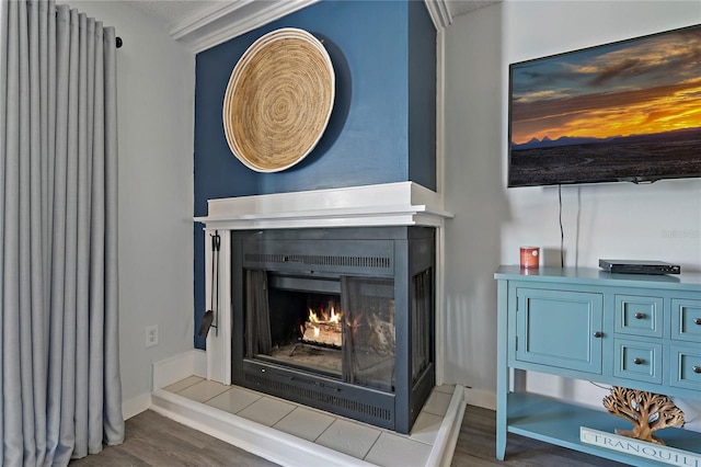 details with baseboards, a lit fireplace, and wood finished floors