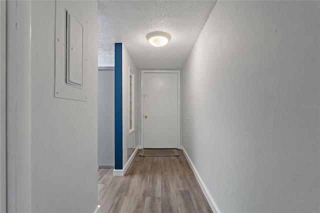 corridor with baseboards, a textured ceiling, and wood finished floors