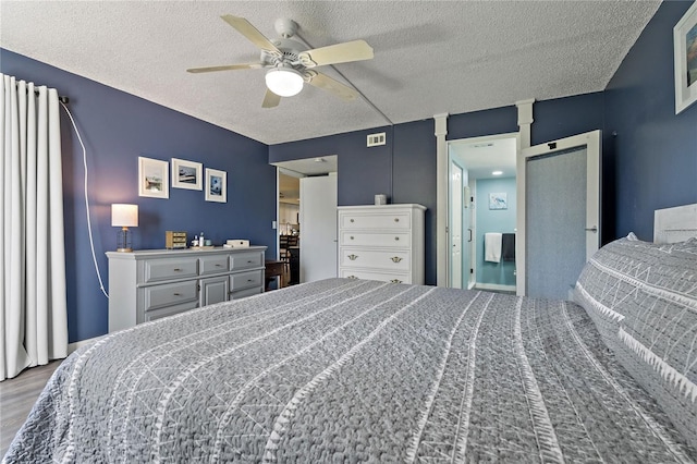 bedroom with visible vents, a textured ceiling, wood finished floors, and a ceiling fan