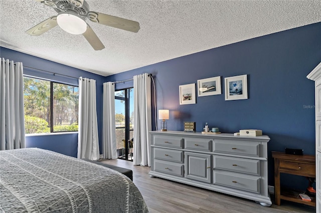 bedroom with a textured ceiling, access to outside, wood finished floors, and ceiling fan