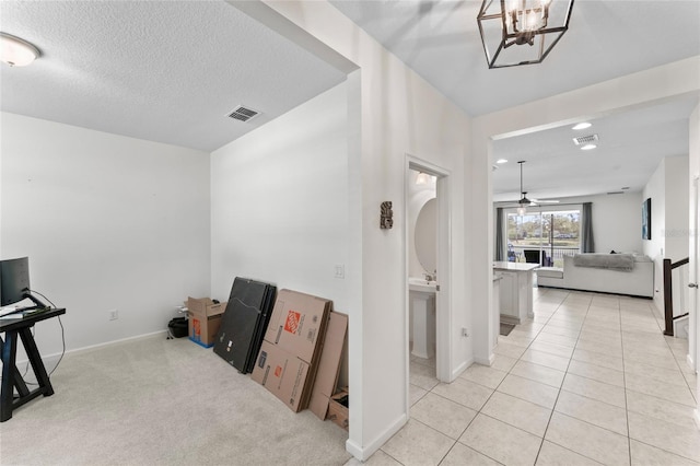 interior space with light tile patterned floors, visible vents, light carpet, and a textured ceiling