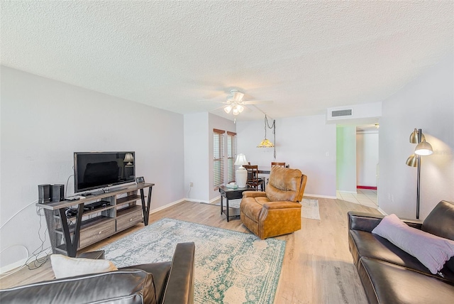 living area with ceiling fan, visible vents, a textured ceiling, and light wood-style flooring