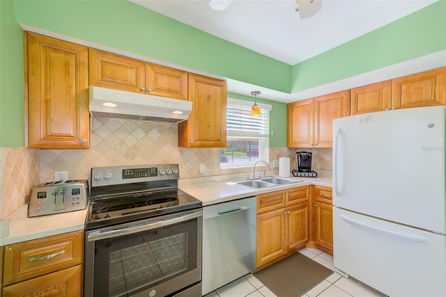 kitchen featuring under cabinet range hood, a sink, appliances with stainless steel finishes, light countertops, and light tile patterned floors