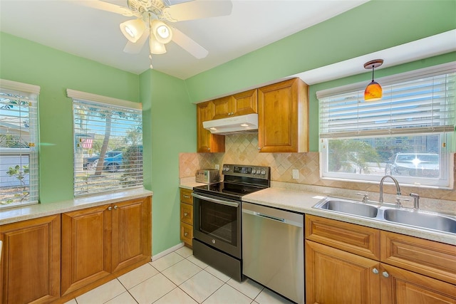 kitchen featuring under cabinet range hood, light countertops, brown cabinetry, stainless steel appliances, and a sink