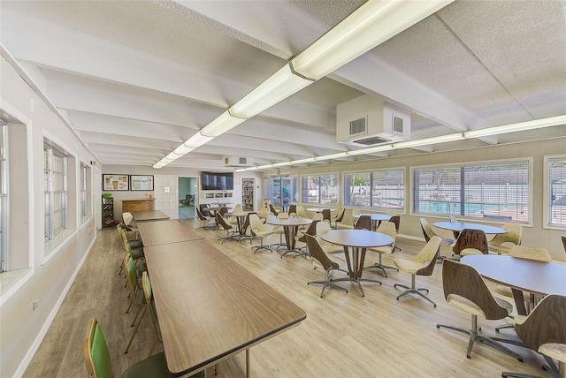 dining space featuring beamed ceiling, a healthy amount of sunlight, baseboards, and wood finished floors