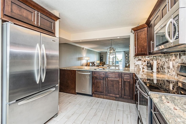 kitchen featuring dark brown cabinetry, light stone counters, decorative backsplash, light wood-style flooring, and appliances with stainless steel finishes