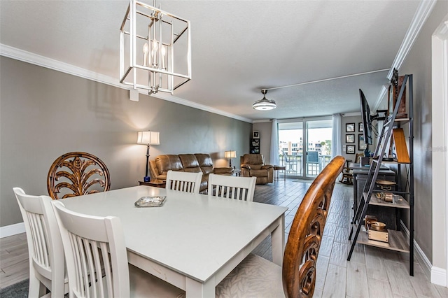 dining area with an inviting chandelier, wood finished floors, baseboards, and ornamental molding