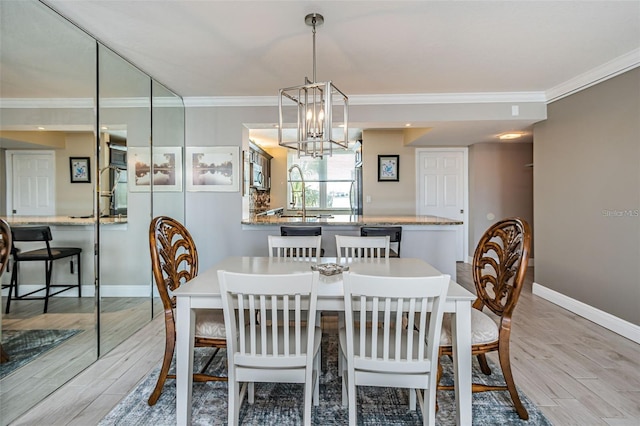 dining area with a chandelier, baseboards, light wood finished floors, and ornamental molding