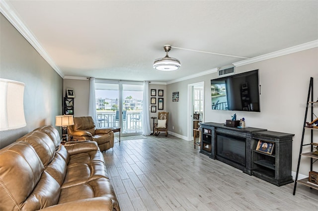 living area with plenty of natural light, light wood-style floors, and ornamental molding