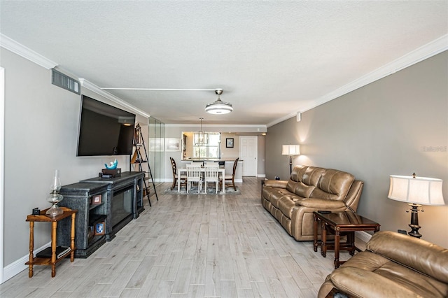 living area with visible vents, baseboards, crown molding, and light wood-style floors