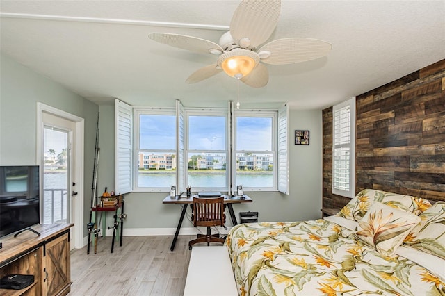 bedroom with wooden walls, light wood-type flooring, and baseboards