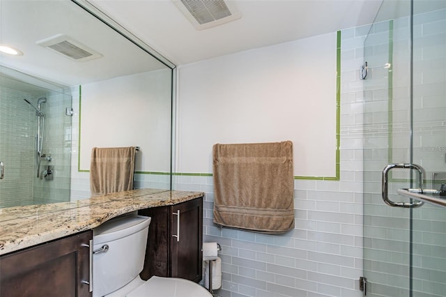 full bathroom featuring visible vents, a shower stall, tile walls, toilet, and vanity