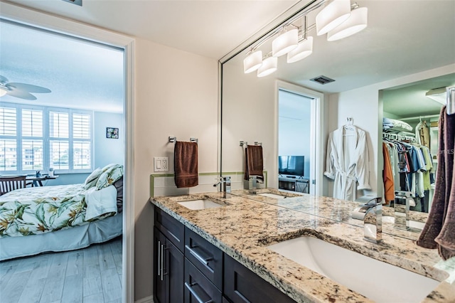 bathroom featuring double vanity, wood finished floors, ensuite bath, and a sink