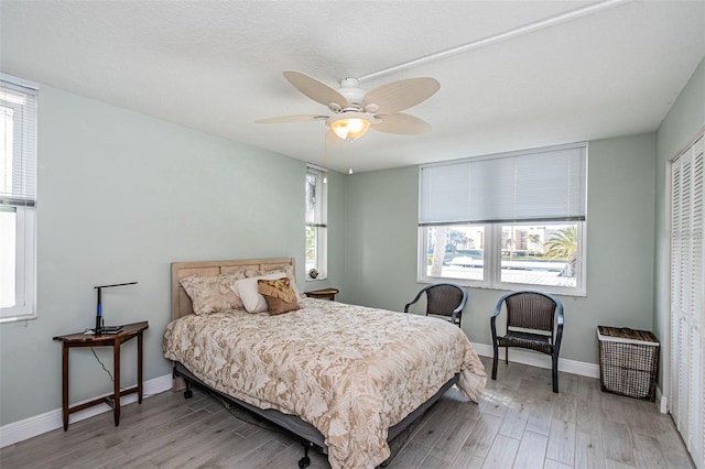 bedroom with ceiling fan, a closet, baseboards, and wood finished floors