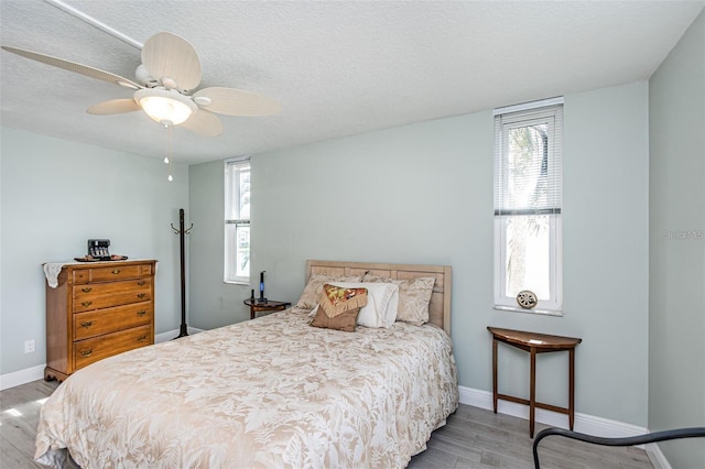 bedroom with multiple windows, baseboards, and wood finished floors