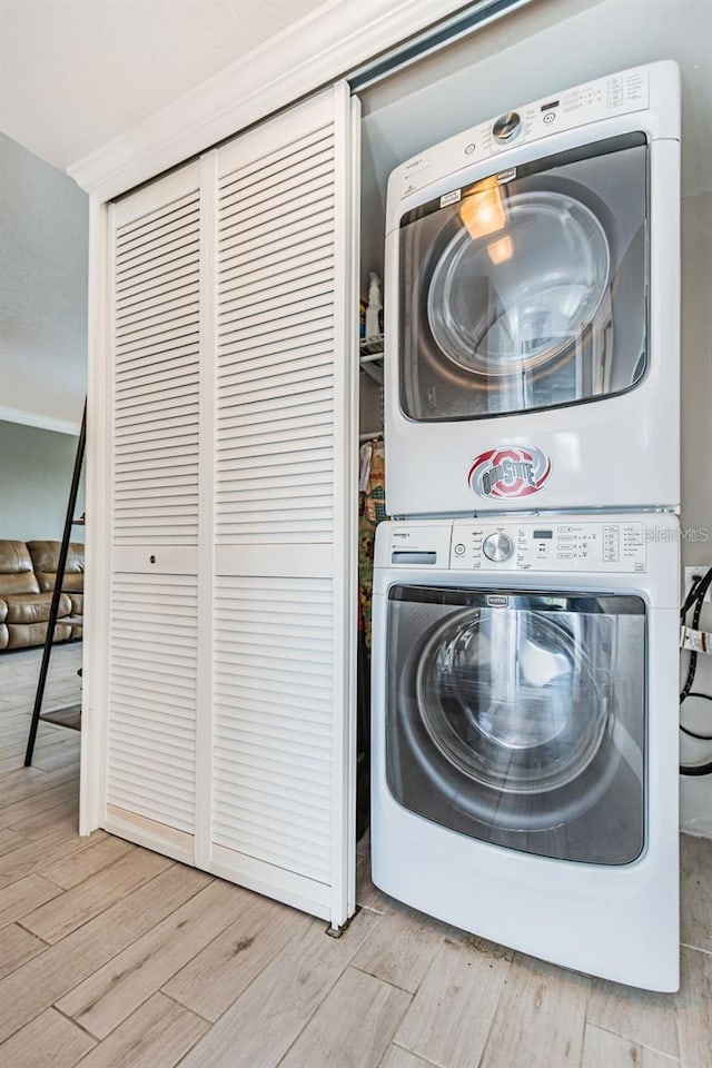 laundry area featuring laundry area, wood finished floors, and stacked washer and dryer