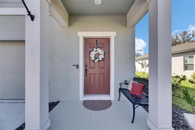 entrance to property with stucco siding and a garage