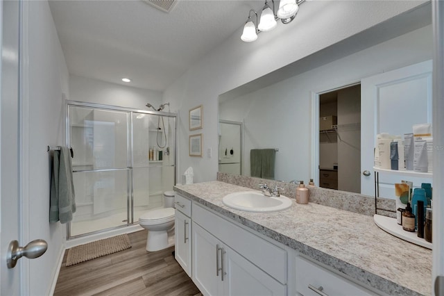 full bath featuring visible vents, toilet, a stall shower, wood finished floors, and vanity