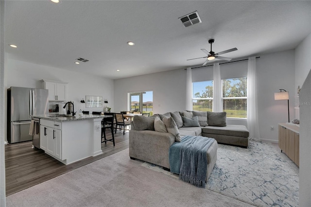 living room featuring wood finished floors, recessed lighting, a ceiling fan, and visible vents
