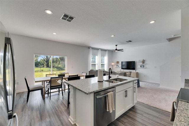 kitchen featuring light stone counters, visible vents, a sink, appliances with stainless steel finishes, and open floor plan