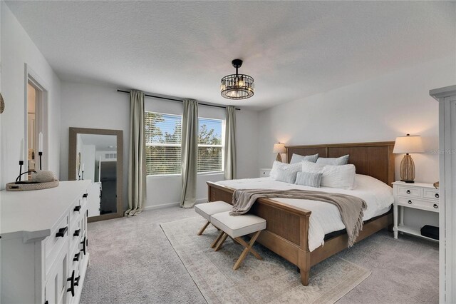 bedroom featuring a textured ceiling, a notable chandelier, and light carpet