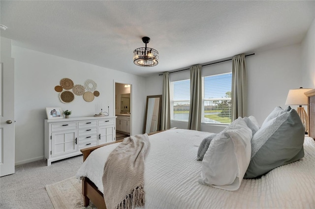 bedroom with baseboards, a chandelier, light carpet, ensuite bath, and a textured ceiling