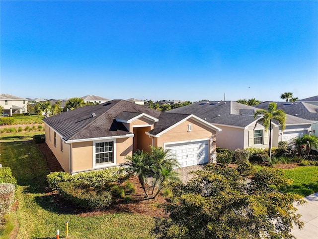 ranch-style home with stucco siding, driveway, a front yard, and an attached garage