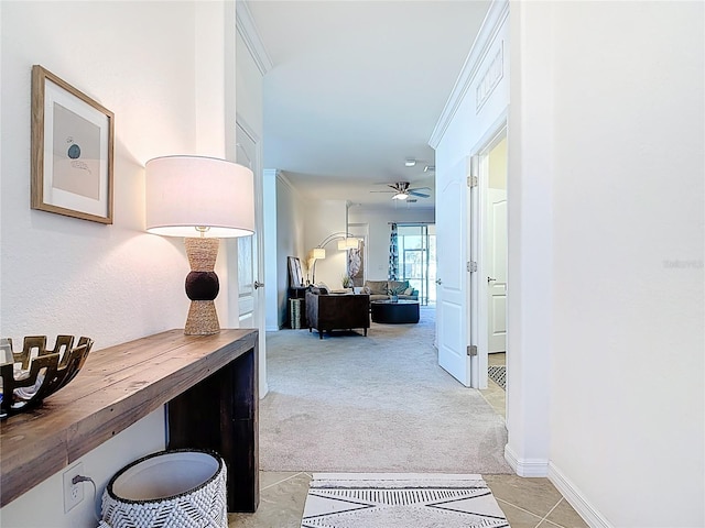 hallway featuring ornamental molding, baseboards, and light carpet