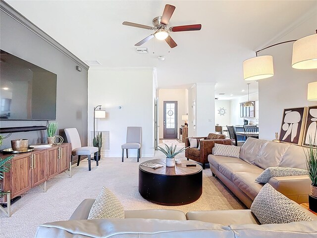 living room featuring visible vents, crown molding, baseboards, ceiling fan, and light carpet