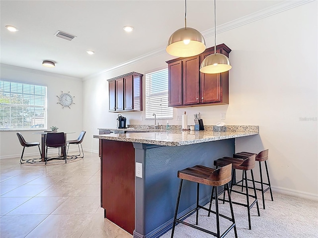 kitchen with a breakfast bar, a peninsula, visible vents, and ornamental molding