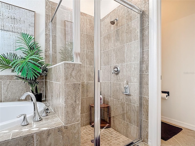 bathroom featuring tile patterned floors, a shower stall, baseboards, and a garden tub