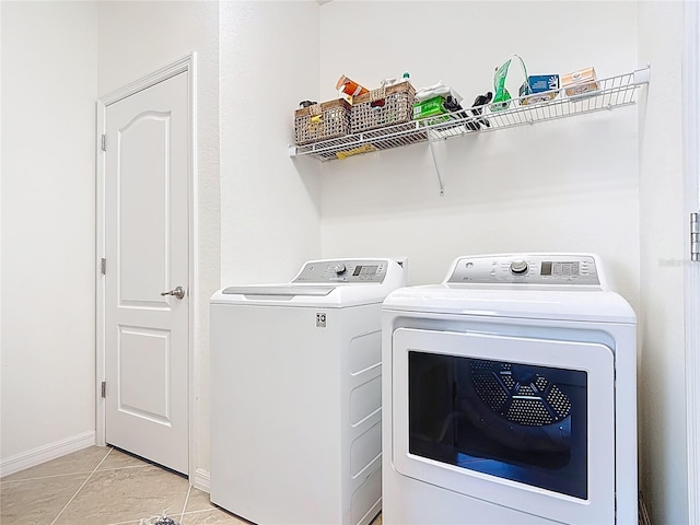 clothes washing area featuring light tile patterned floors, laundry area, baseboards, and separate washer and dryer