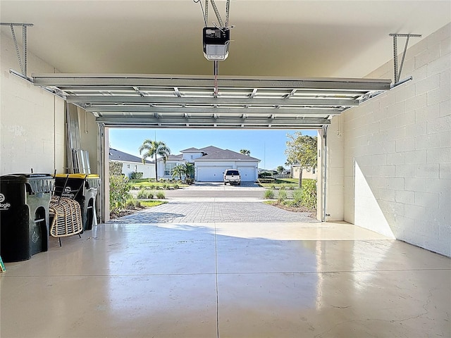 garage featuring concrete block wall and a garage door opener